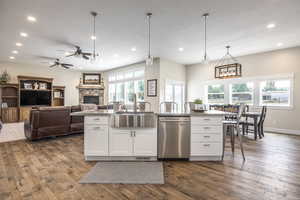 Kitchen featuring sink, dishwasher, a kitchen island with sink, and white cabinets