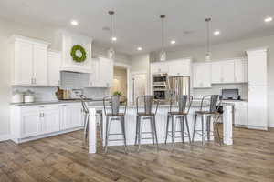 Kitchen featuring white cabinetry, appliances with stainless steel finishes, and decorative light fixtures