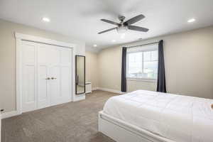 Carpeted bedroom with a closet and ceiling fan