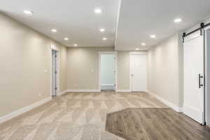 Basement featuring a barn door, light carpet, and a textured ceiling