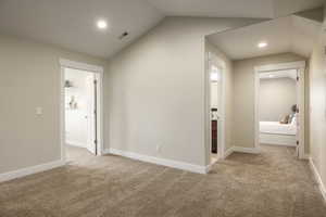 Hallway with lofted ceiling and light carpet