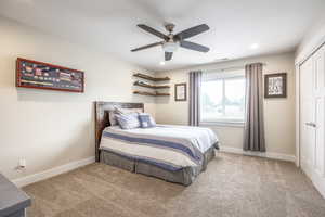 Carpeted bedroom featuring a closet and ceiling fan