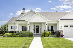 View of front of house featuring a garage, covered porch, and a front yard