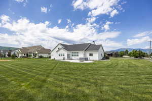 Back of house featuring a patio, a mountain view, and a yard