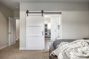 Bedroom featuring a barn door and carpet flooring