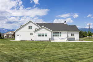 Rear view of property featuring a hot tub, a mountain view, a yard, and a patio area