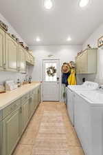 Laundry room with separate washer and dryer, sink, light tile patterned floors, and cabinets