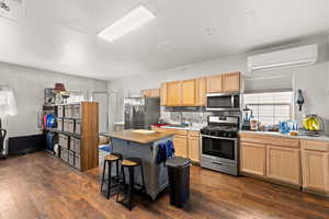 Kitchen featuring sink, backsplash, a wall unit AC, stainless steel appliances, and dark hardwood / wood-style floors