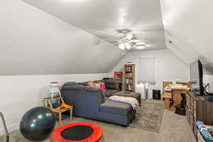 Living room featuring light carpet, ceiling fan, vaulted ceiling, and a textured ceiling