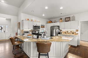 Kitchen with white cabinetry, appliances with stainless steel finishes, and a breakfast bar area