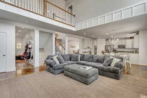 Living room with a chandelier, a high ceiling, and light hardwood / wood-style flooring