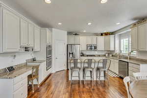 Kitchen with white cabinetry, a center island, appliances with stainless steel finishes, and a kitchen breakfast bar