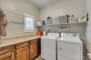 Laundry room featuring washing machine and dryer, light wood-type flooring, and cabinets