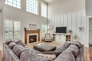 Living room featuring hardwood / wood-style flooring, a high ceiling, and a fireplace