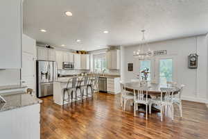 Dining area with an inviting chandelier, dark wood-type flooring, and a textured ceiling