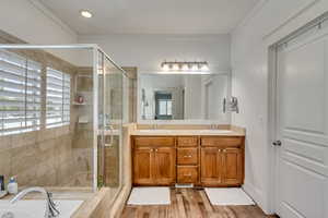 Bathroom with vanity, a wealth of natural light, shower with separate bathtub, and ornamental molding