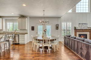 Dining area featuring a fireplace, dark hardwood / wood-style flooring, a notable chandelier, and a healthy amount of sunlight