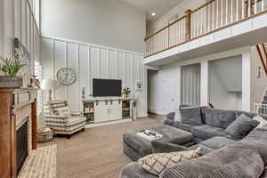 Carpeted living room with a towering ceiling and a brick fireplace