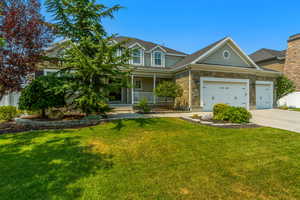 View of front of house with a garage, covered porch, and a front yard