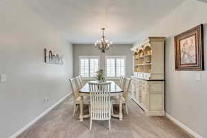 Carpeted dining area with a textured ceiling and an inviting chandelier