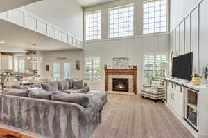 Carpeted living room featuring a chandelier, a brick fireplace, and a high ceiling