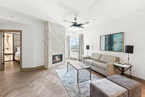 Living room with parquet flooring, a premium fireplace, and ceiling fan