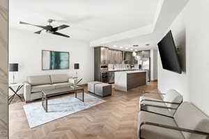 Living room featuring ceiling fan, sink, and light parquet flooring