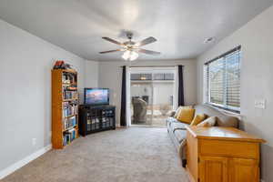 Carpeted living room with ceiling fan and a textured ceiling