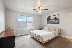 Carpeted bedroom with a textured ceiling and ceiling fan