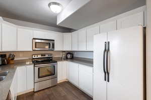 Kitchen with sink, appliances with stainless steel finishes, dark hardwood / wood-style floors, a textured ceiling, and white cabinets