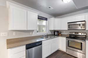 Kitchen featuring appliances with stainless steel finishes, dark hardwood / wood-style flooring, sink, and white cabinets