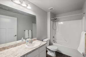 Full bathroom featuring vanity, hardwood / wood-style floors,  shower combination, and toilet