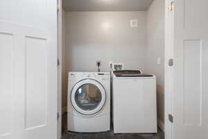 Laundry area with washer and dryer and dark wood-type flooring