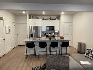 Kitchen featuring a kitchen bar, white cabinets, appliances with stainless steel finishes, and an island with sink