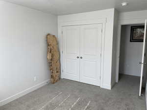 Unfurnished bedroom featuring a closet, a textured ceiling, and carpet floors