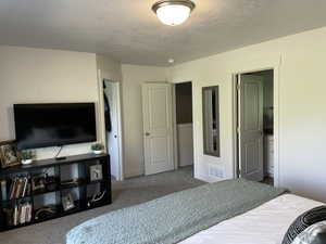 Bedroom with dark carpet and a textured ceiling