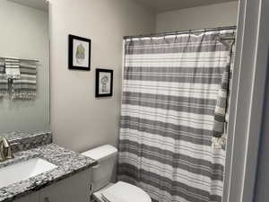 Bathroom with curtained shower, toilet, and vanity