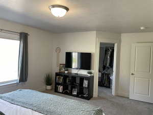 Carpeted bedroom featuring a textured ceiling and a closet