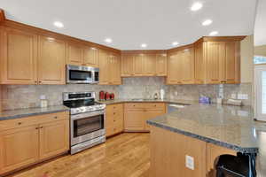 Kitchen featuring hardwood flooring, stainless steel appliances, and charming backsplash