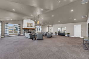 Carpeted living room featuring high vaulted ceiling and a fireplace