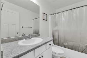 Full bathroom featuring toilet, vanity, and shower / bathtub combination with curtain