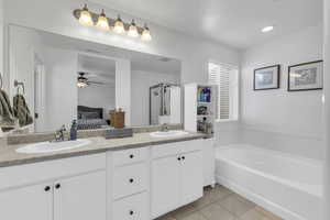 Bathroom featuring ceiling fan, tile patterned floors, vanity, and a bathing tub