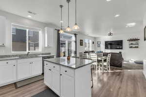 Kitchen featuring stone countertops, decorative light fixtures, dishwasher, sink, and white cabinets