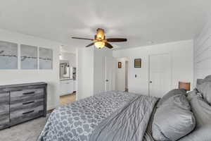 Carpeted bedroom with ceiling fan and ensuite bathroom