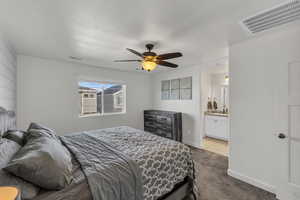 Bedroom with ceiling fan, ensuite bath, and light carpet