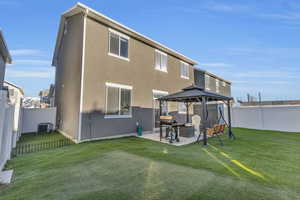 Rear view of house featuring a gazebo, cooling unit, a patio area, and a lawn