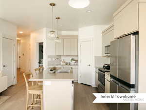 Kitchen featuring backsplash, decorative light fixtures, stainless steel appliances, and an island with sink