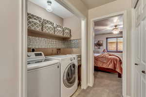 Laundry room with light carpet, ceiling fan, and washing machine and clothes dryer