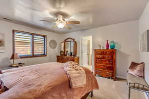 Bedroom with light carpet, a textured ceiling, and ceiling fan