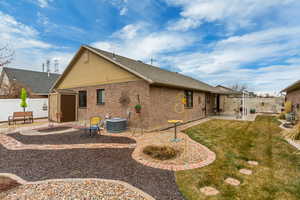 Rear view of property with cooling unit, a storage unit, a yard, and a patio